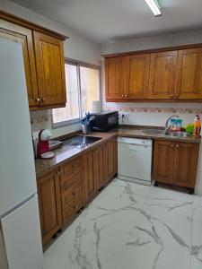 a kitchen with wooden cabinets and a marble floor at Bellavista in La Línea de la Concepción
