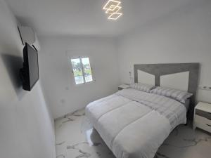 a white bedroom with a bed and a tv at Bellavista in La Línea de la Concepción