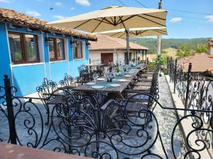 a long table with chairs and an umbrella at Old House - Стара Къща in Koprivshtitsa