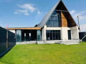a building with a pointed roof and a grass yard at Arinest Villa with heated pool, 20 min from Yerevan in Elar