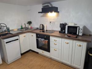 a kitchen with white cabinets and a microwave and a stove at Old House - Стара Къща in Koprivshtitsa