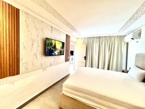 a bedroom with a bed and a tv on a wall at Lovely studio 4th floor No Elevator in El Gouassem