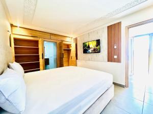 a bedroom with a large white bed and a tv at Lovely studio 4th floor No Elevator in El Gouassem