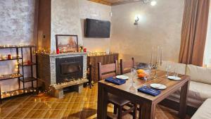 een woonkamer met een tafel en een open haard bij Комплекс БОЖИДАРИЦА in Progled