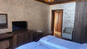 een slaapkamer met twee bedden en een flatscreen-tv bij Комплекс БОЖИДАРИЦА in Progled +103 foto's