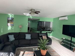 a living room with a black couch and green walls at Toraille Waterfall Poolside Apartment in Soufrière