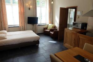 a hotel room with a bed and a couch and a tv at Nice studio in 16th century castle in Aywaille