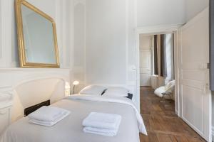 a white bedroom with two beds and a mirror at L'Horloge by Cocoonr in Rennes