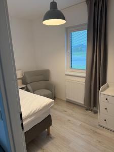 a bedroom with a bed and a chair and a window at Oáza Living Mohelnice in Mohelnice