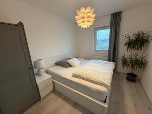 a small bedroom with a bed and a chandelier at Oáza Living Mohelnice in Mohelnice