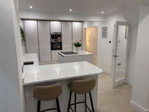 a kitchen with a white counter and two stools at Santíago Retreat in Wenvoe