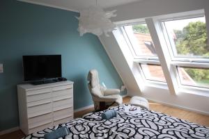 a bedroom with a bed and a tv and windows at Urlaubswerft-Dock-13-|-Ihr-stilvolles-Erholungsparadies in Kiel