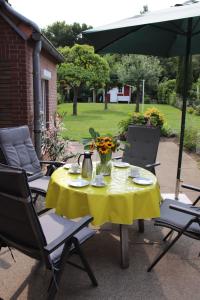 a table with a yellow tablecloth and chairs under an umbrella at Urlaubswerft-Dock-13-|-Ihr-stilvolles-Erholungsparadies in Kiel