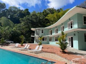 a house with a swimming pool in front of it at Toraille Waterfall Poolside Apartment in Soufrière