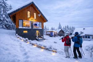 due persone in piedi fuori da una baita nella neve di Chata MartinSki Martinske hole a Martinské Hole