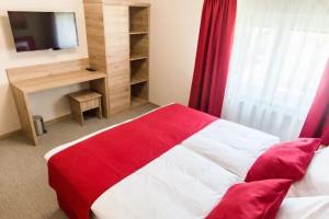 a bedroom with a red and white bed and a television at EnDi Rooms in Ljubljana