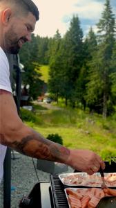 Un uomo sta cucinando cibo su una griglia di Chata MartinSki Martinske hole a Martinské Hole
