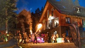 un gruppo di persone in piedi fuori da una casa con il fuoco di Chata MartinSki Martinske hole a Martinské Hole