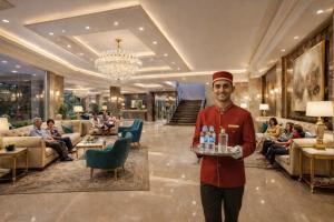 a man in a hotel with a tray of drinks at Hotel The Prithvi Near Delhi Airport in New Delhi