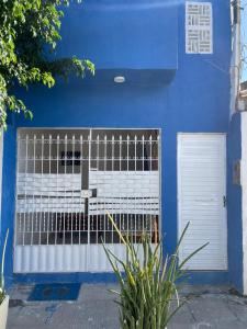 a blue building with a gate and a door at Ster Suítes in Maceió