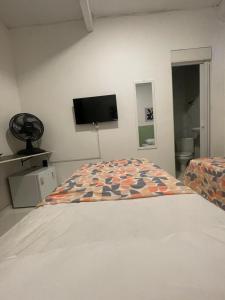 a bedroom with a bed and a flat screen tv at Ster Suítes in Maceió