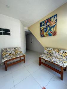 two benches in a room with a painting on the wall at Ster Suítes in Maceió