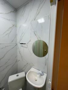 a white bathroom with a sink and a mirror at Ster Suítes in Maceió