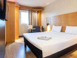ein Hotelzimmer mit einem großen Bett und einem Stuhl in der Unterkunft Ibis Alcala de Henares La Garena in Alcalá de Henares + 129 Fotos