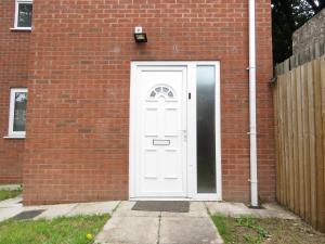 een witte deur aan de zijkant van een bakstenen gebouw bij Tudors eSuites - Central 4 bedroom house #14NS in Birmingham