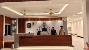 two men standing at a reception desk in a lobby at Hotel Yathra Athithya in Dharmastala