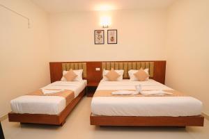 a bedroom with two beds with white sheets at Hotel Yathra Athithya in Dharmastala