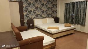 a small room with two beds and a chair at Hotel Shri Shiv Sai in Shirdi +22 photos