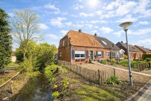 een stenen huis met een hek naast een rivier bij Huus an`t Dörpsdiek in Krummhörn