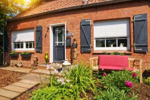 een bakstenen huis met een rode stoel in de tuin bij Huus an`t Dörpsdiek in Krummhörn