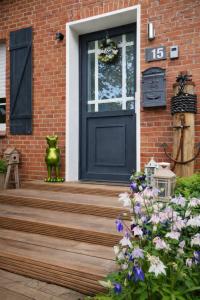een zwarte deur op een bakstenen huis met bloemen bij Huus an`t Dörpsdiek in Krummhörn