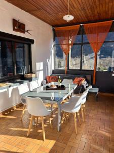 a dining room with a glass table and white chairs at La maison Bellevue in Antignac