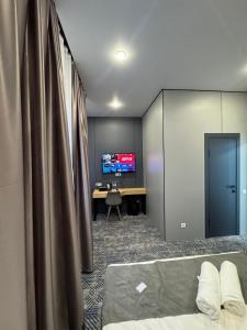 a room with a bed and a desk with a television at Home Inn Hotel in Almaty