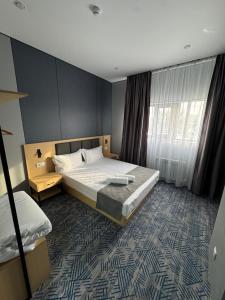 a hotel room with a bed and a window at Home Inn Hotel in Almaty