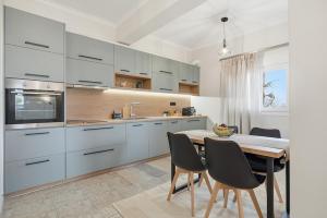 a kitchen with white cabinets and a table and chairs at Calma Ioannina Apartment in Ioannina