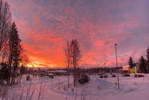 a sunset over a parking lot with snow and cars at Kotkanpesä in Ylläs