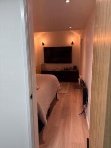 a bedroom with a bed and a flat screen tv at The Cozy Forge in Horley