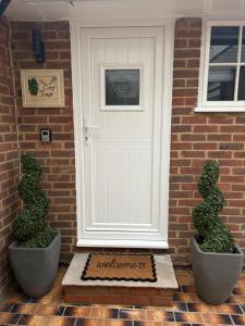 a white door on a brick house with two bushes at The Cozy Forge in Horley