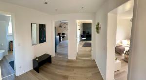 Ein Flur führt zu einem Wohnzimmer mit weißen Wänden in der Unterkunft Eifelpause Vulkan in Bleckhausen