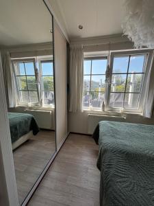 a mirror in a bedroom with two beds and windows at Ferienhaus Breskens in Breskens
