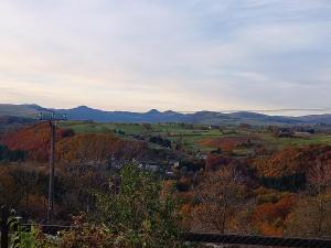 a view of a valley with fall trees and mountains at Chambres d'hôtes du Chênelong Cantal in Marchastel