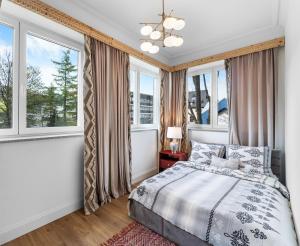 a bedroom with windows and a bed and a chandelier at Willa Monte in Zakopane