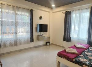 a room with a bed and a tv and windows at Cleanslate homestay in Guwahati +13 photos