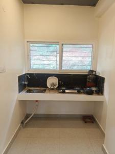 a kitchen counter with a sink and two windows at Cleanslate homestay in Guwahati