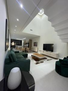 a living room with a green couch and a tv at Maison Joia dos Vinhedos in Vinhedo