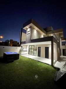 a large white house with a green lawn at night at Maison Joia dos Vinhedos in Vinhedo
